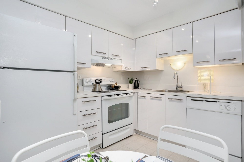 a white kitchen with white cabinets and appliances and a table and chairs