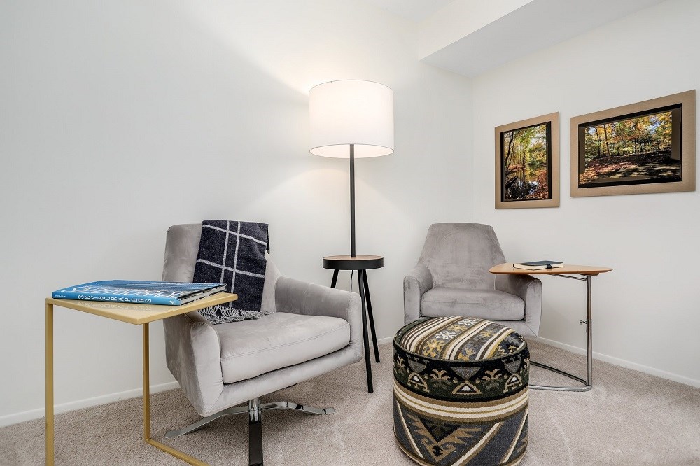 a living room with two chairs and a table and a lamp