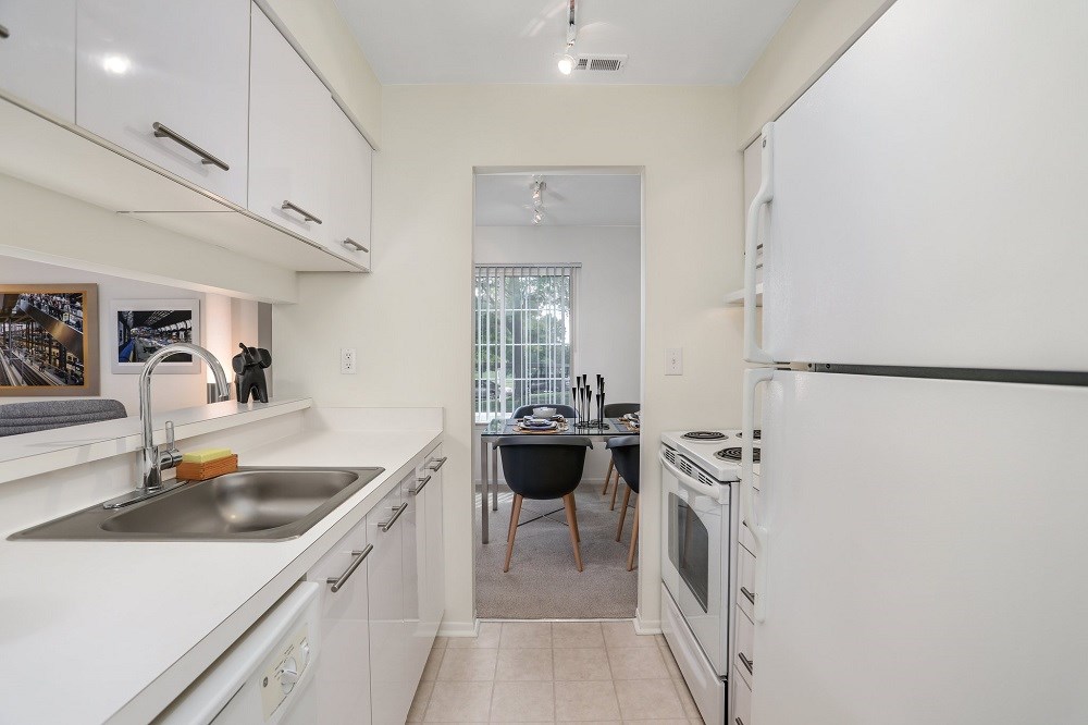 a kitchen with white appliances and white cabinets and a table with a chair