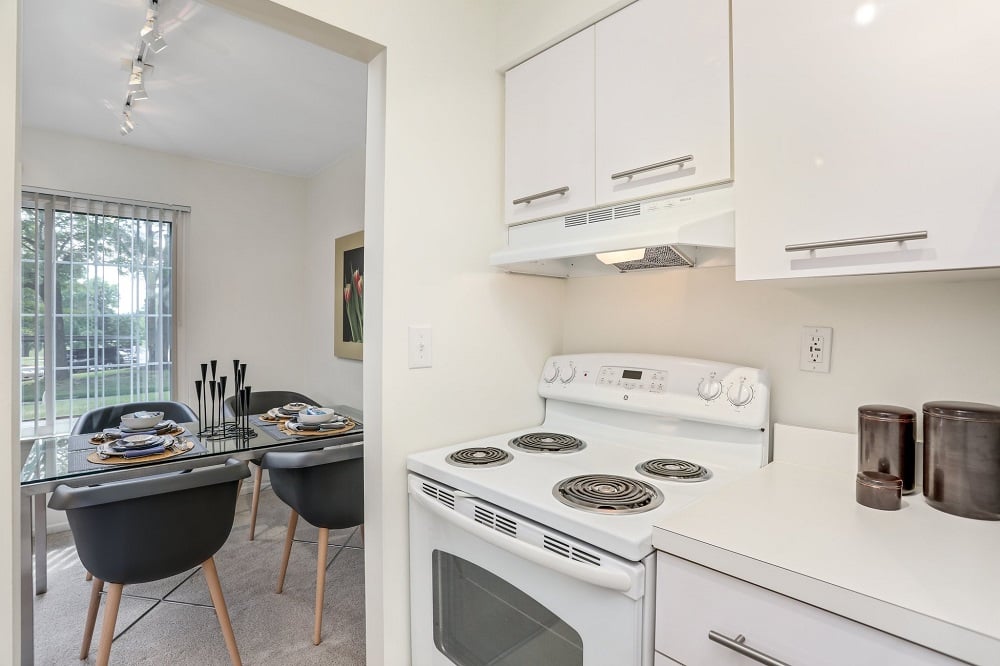 A white stove is in a kitchen with white cabinets.