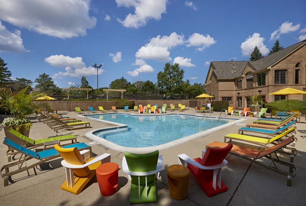 a swimming pool with colorful chairs around it in front of a house