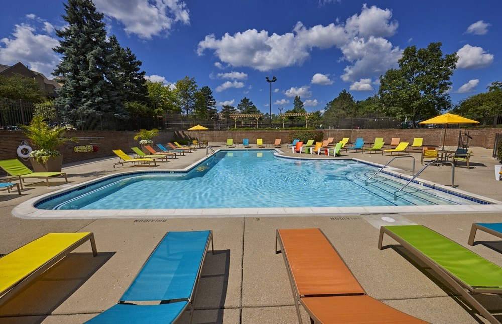 our resort style pool is filled with lounge chairs and umbrellas
