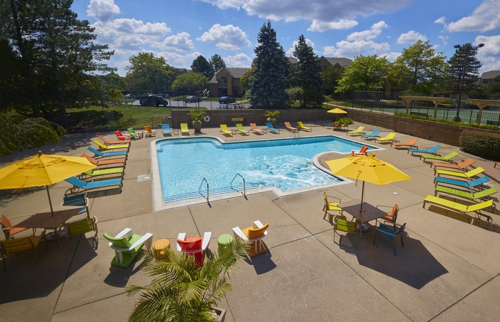 a resort style pool with lounge chairs and umbrellas