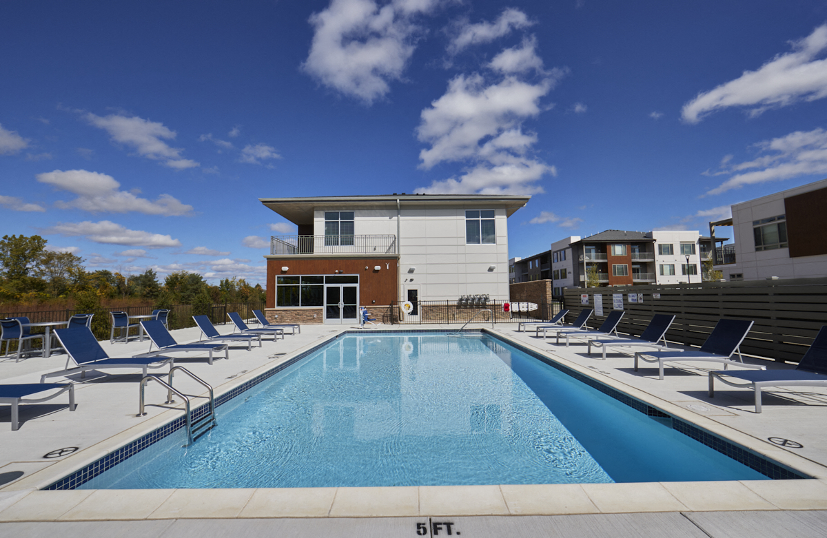 a pool with blue lounge chairs and a building in the background