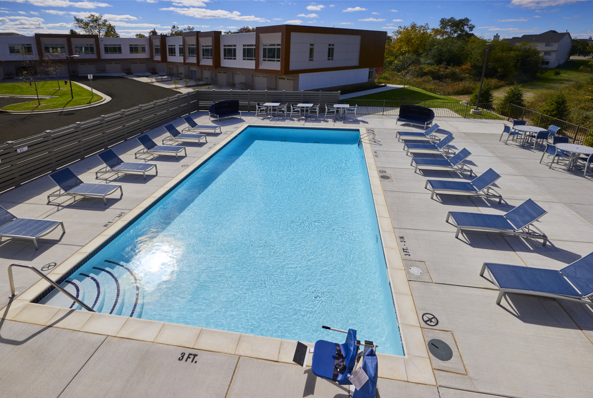 an aerial view of a swimming pool with blue chairs around it