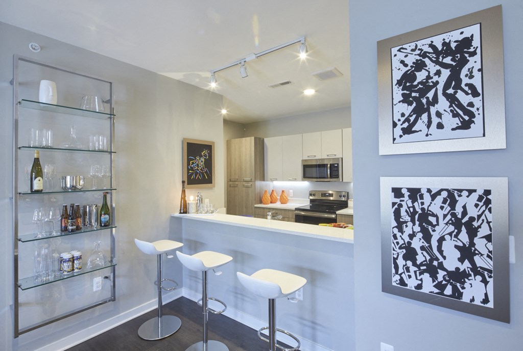 a kitchen with a bar and stools in front of a counter and a refrigerator