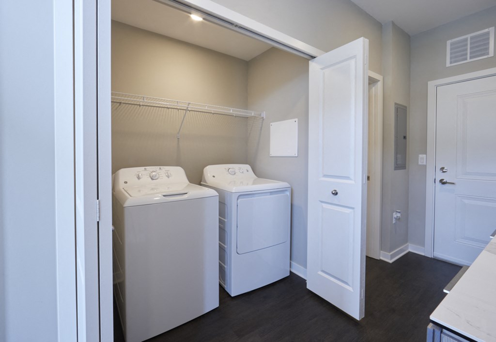 an empty laundry room with washers and dryers and a door to a closet