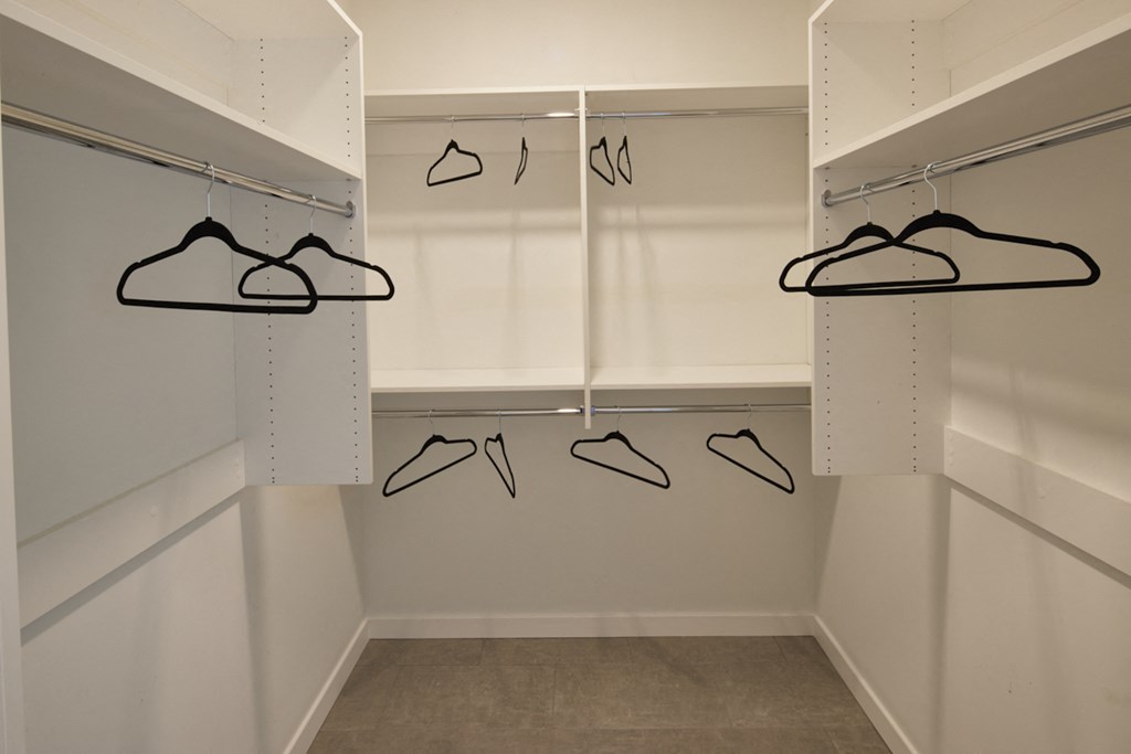 a walk in closet with a row of hangers of shoes