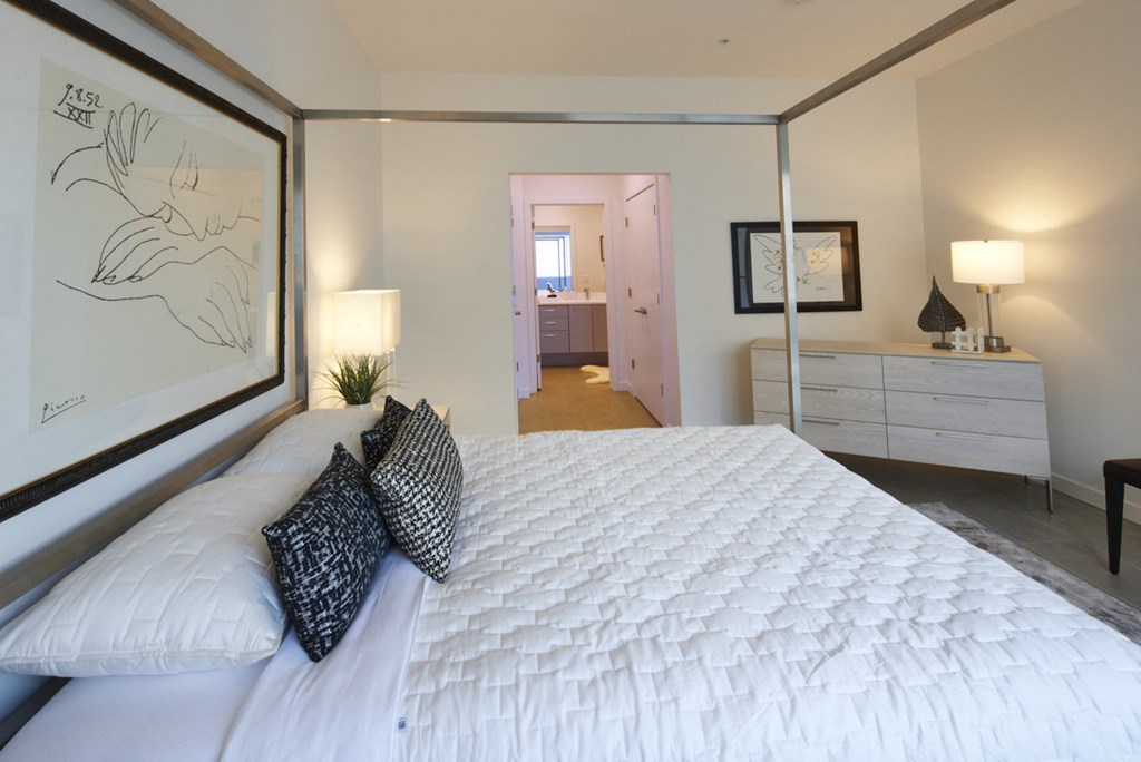 a bedroom with a large white bed and a large mirror
