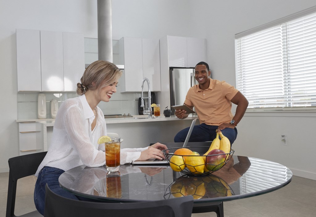 a man and woman sitting at a kitchen table with a bowl of fruit