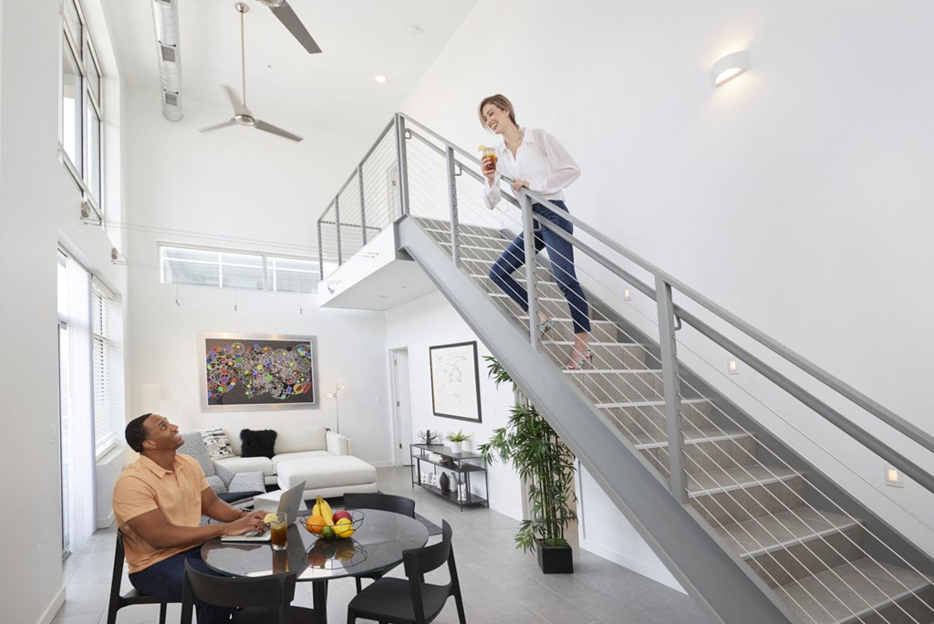 a woman walking up a stairs in a house with a man sitting at a table