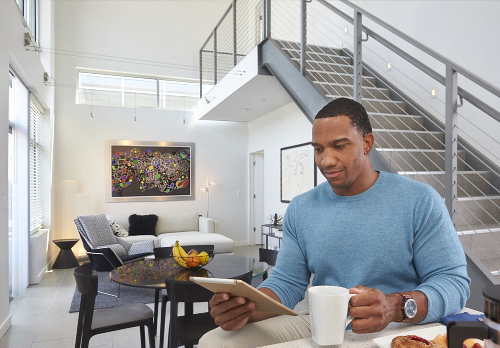 a man sitting at a table with a cup of coffee looking at a tablet computer