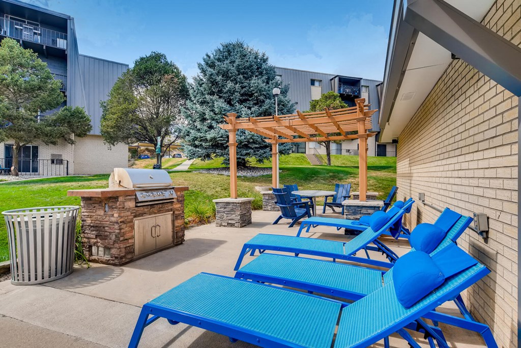 a patio with blue chairs and a grill and a picnic table