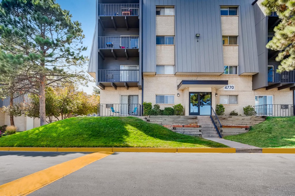 front view of an apartment building with stairs and grass