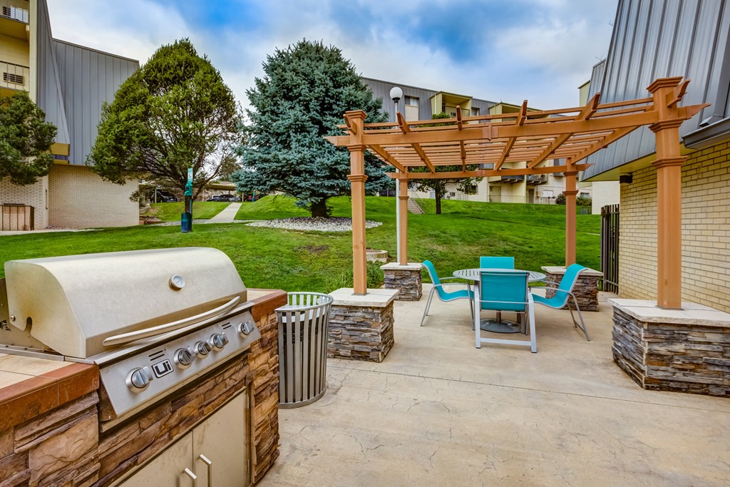 a patio with a barbecue grill and a table and chairs