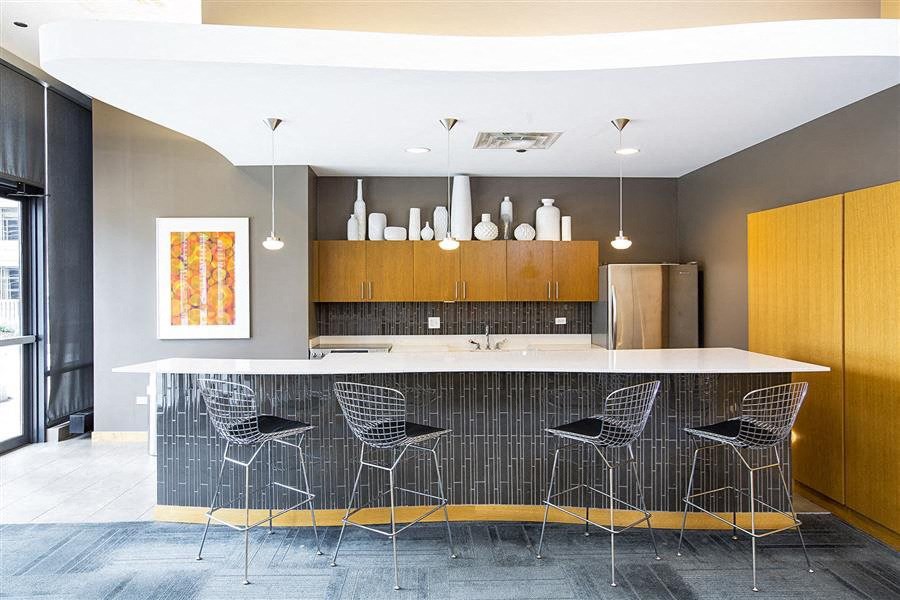 a modern kitchen with a bar and chairs