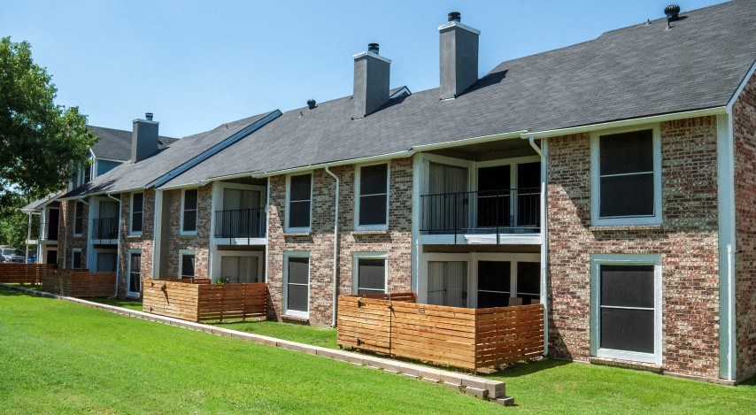 a row of brick apartment buildings with a green lawn