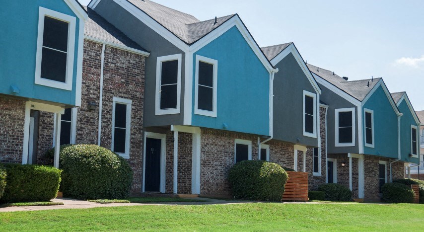 a row of houses with blue roofs and green grass