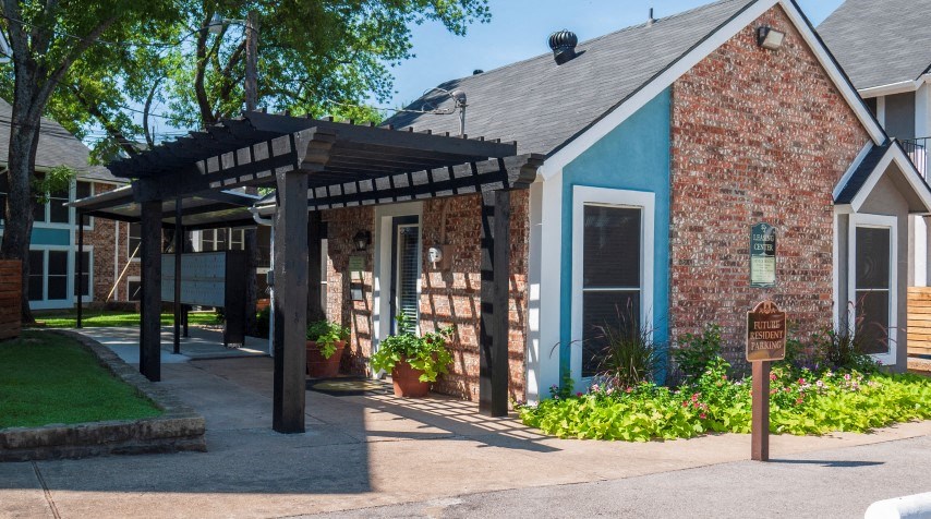 a small brick building with a porch and a blue building
