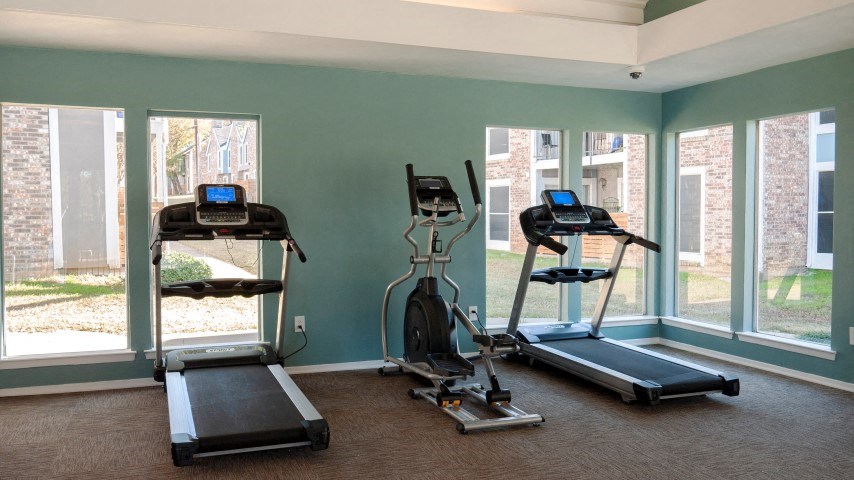 three exercise machines in a room with three windows