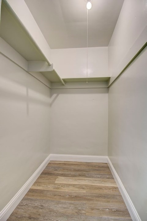 A long, narrow hallway with wood flooring and white walls.