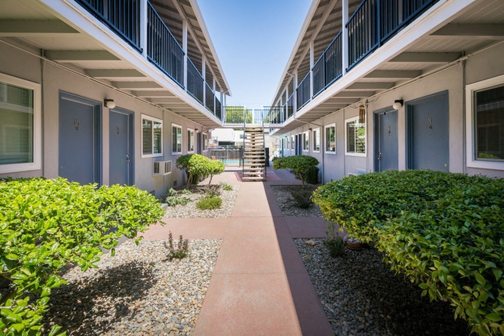 the courtyard of a building with bushes and a staircase