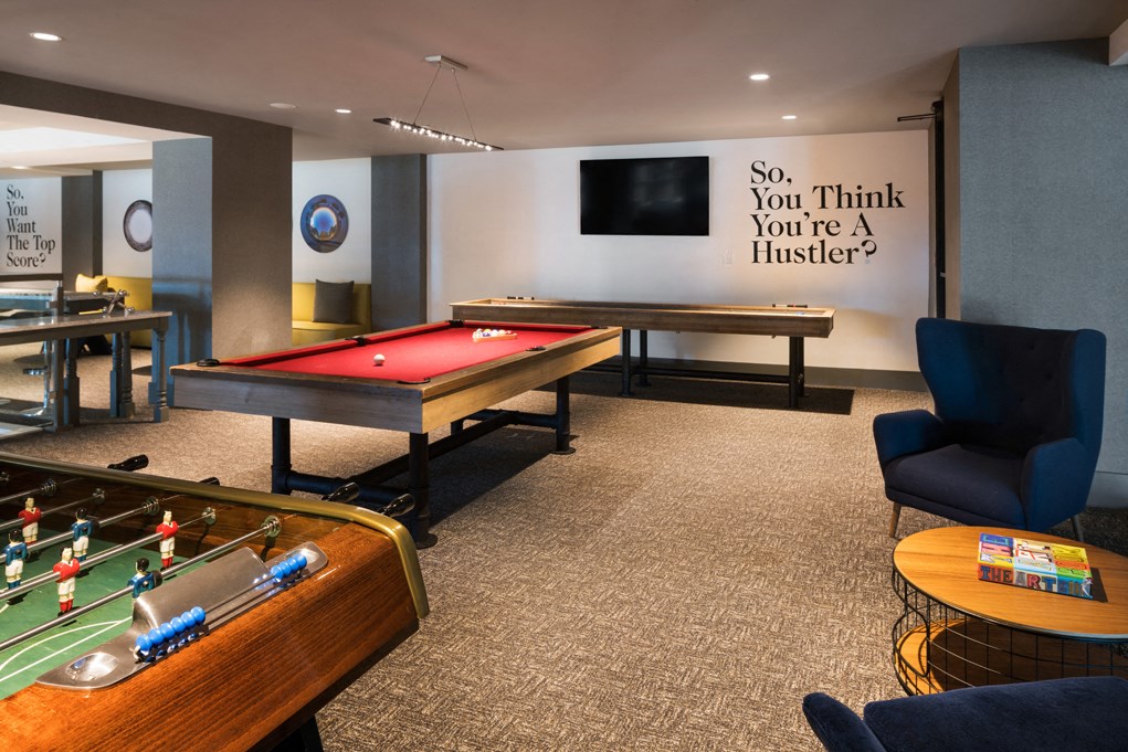 a game room with two pool tables and a large sign saying so you think you