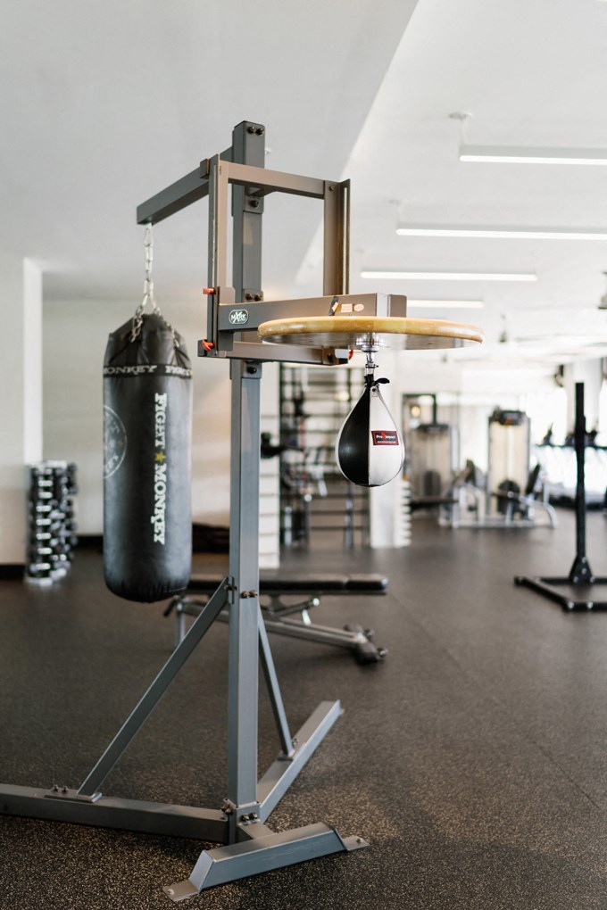 two boxing bags hanging from a rack in a gym