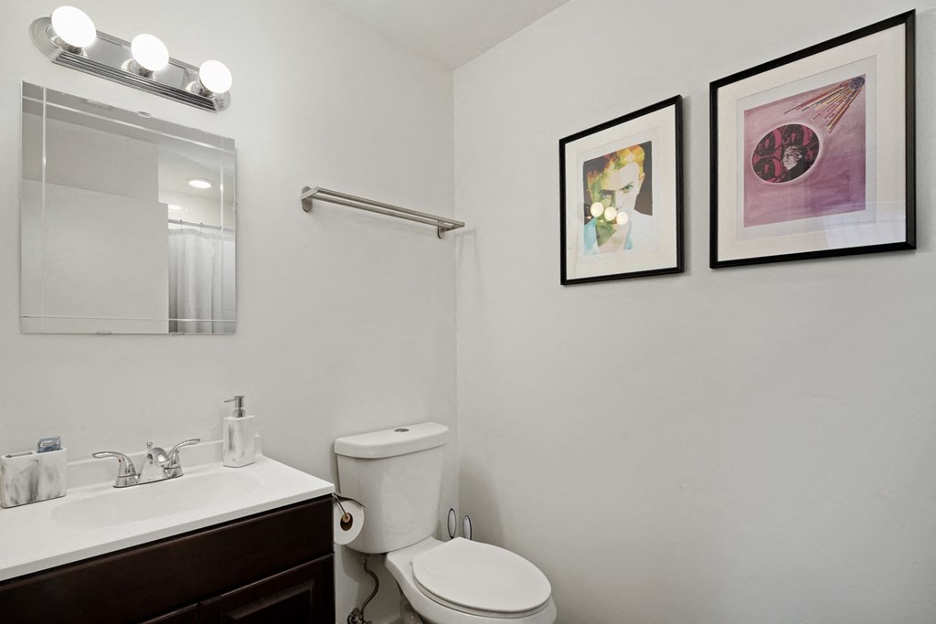 a bathroom with two pictures on the wall and a toilet and sink
