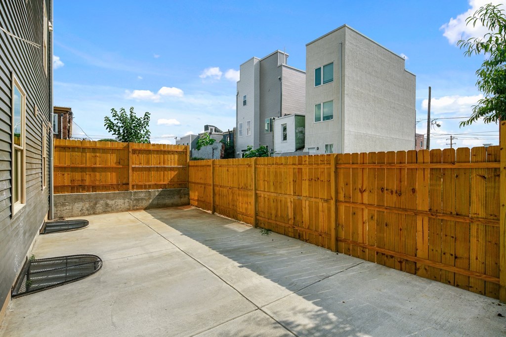 a backyard with a wooden privacy fence and apartment buildings behind it