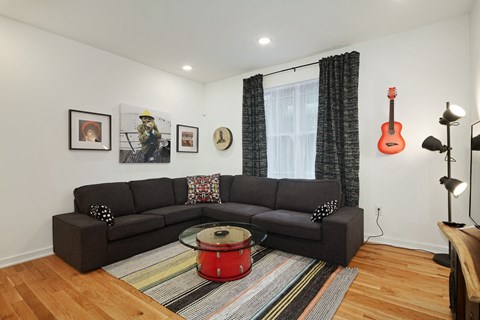 a living room with a couch and a guitar on the wall