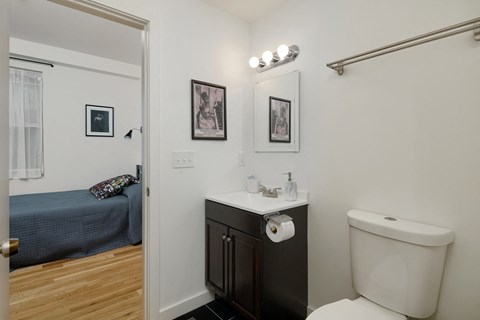 a bathroom with a toilet sink and mirror and a bedroom with a bed