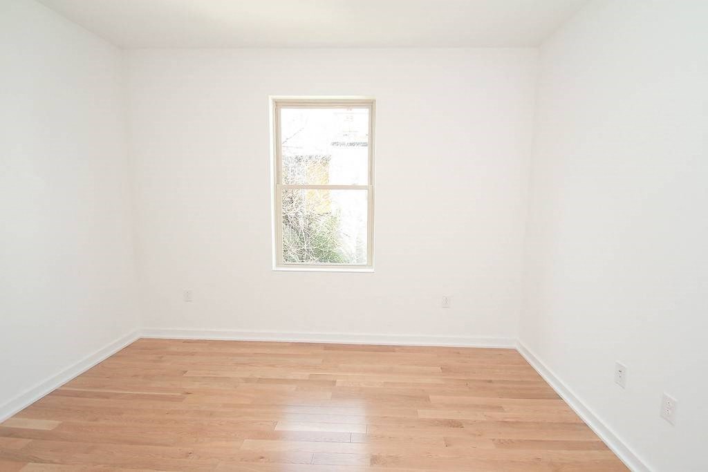 an empty room with a window and wooden floors