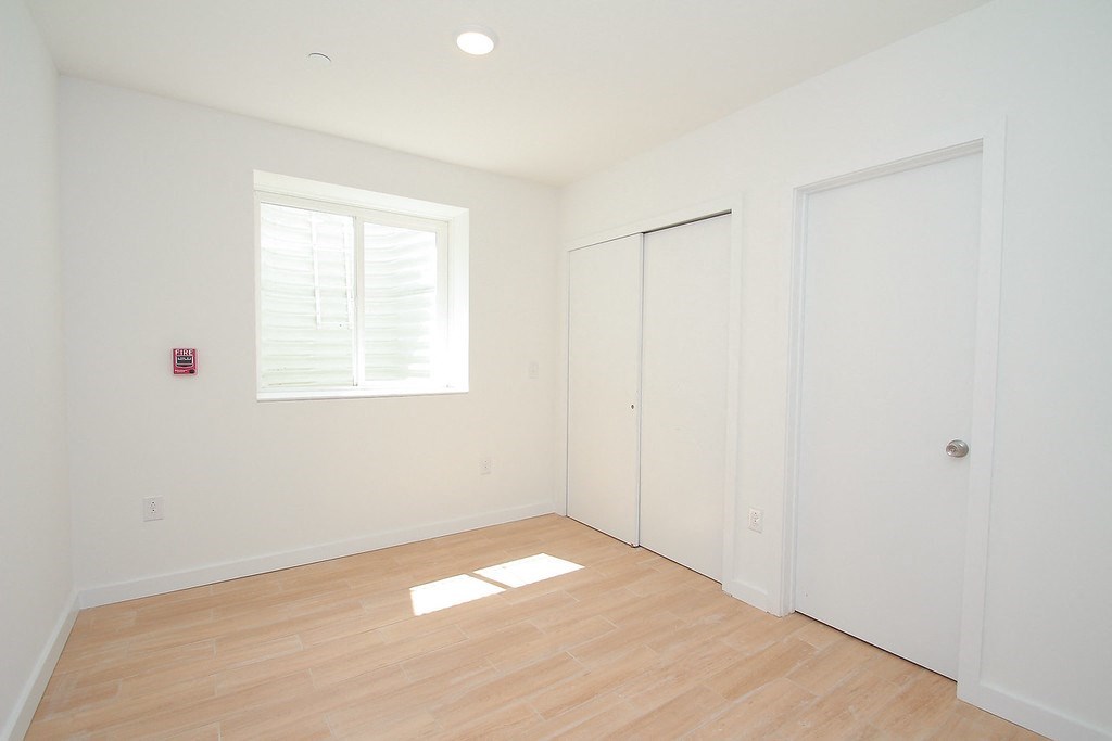 an empty room with white walls and a window and wooden floors