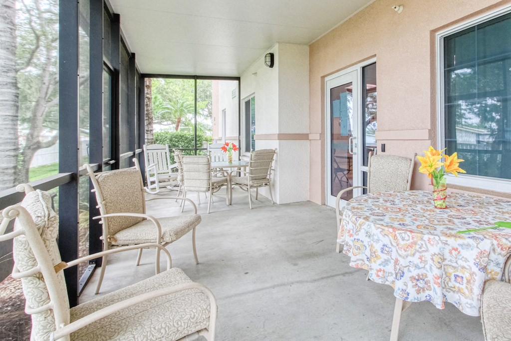 a covered porch with tables and chairs and windows