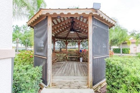a wooden gazebo with a table in a garden