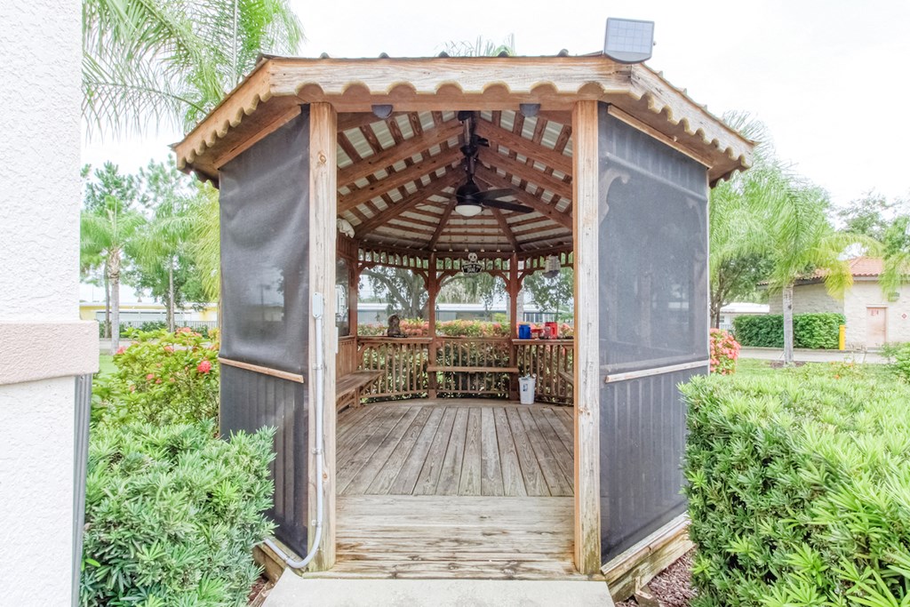 a wooden gazebo with a table in a garden