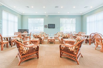 community room with large windows, tables, chairs, and TV