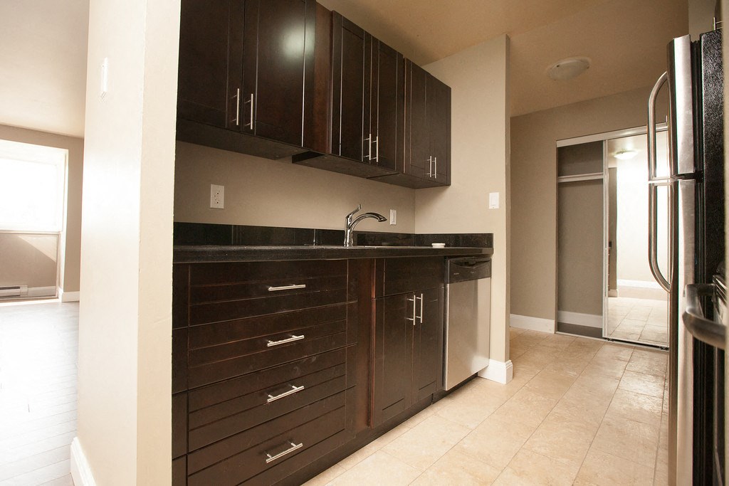 a kitchen with dark wood cabinets and a stainless steel refrigerator