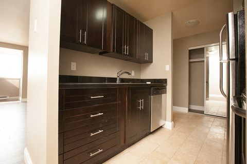 a kitchen with dark wood cabinets and a stainless steel refrigerator