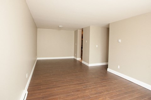 an empty living room with wood flooring and white walls