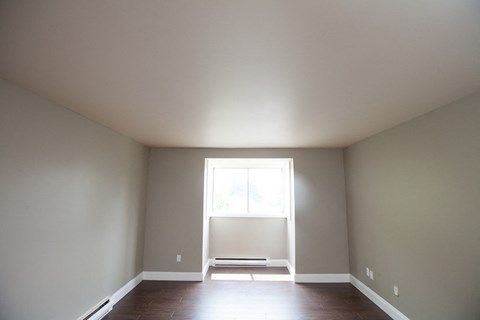an empty room with a window and wooden floors