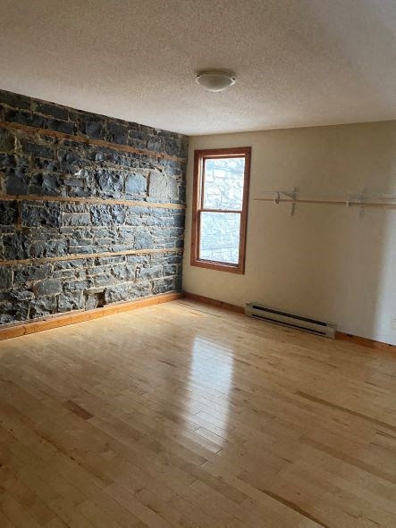 an empty living room with a stone wall and wood floors