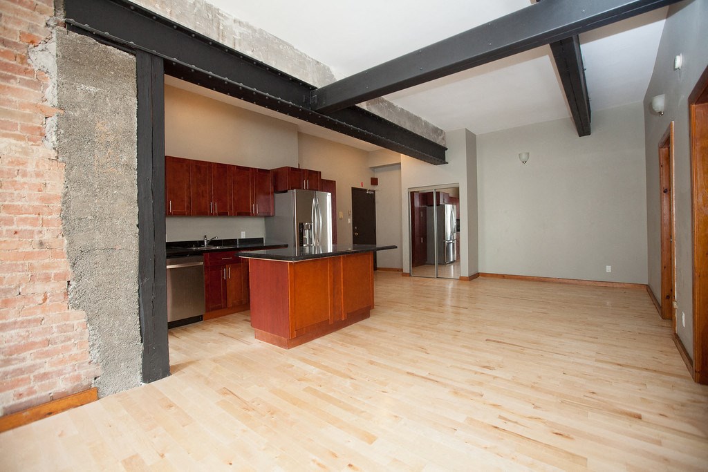 a kitchen with a wooden floor and a large exposed brick wall