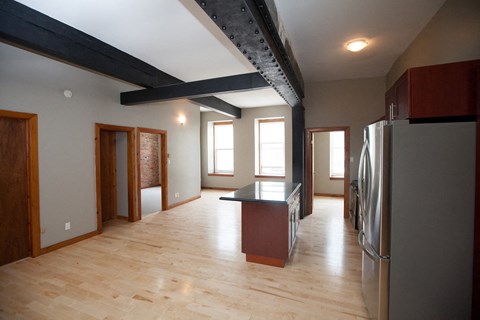 a kitchen with a wooden floor and a stainless steel refrigerator