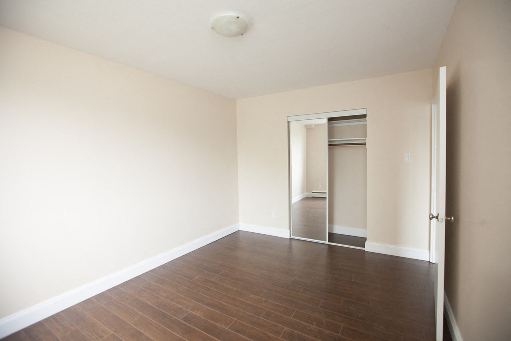 an empty living room with wood flooring and white walls