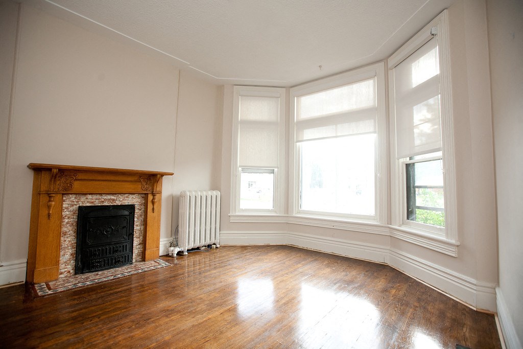 an empty living room with a fireplace and wood floors