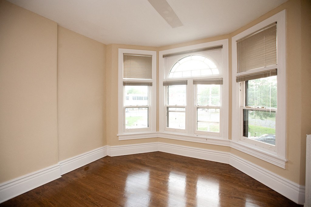 an empty room with three windows and a wooden floor