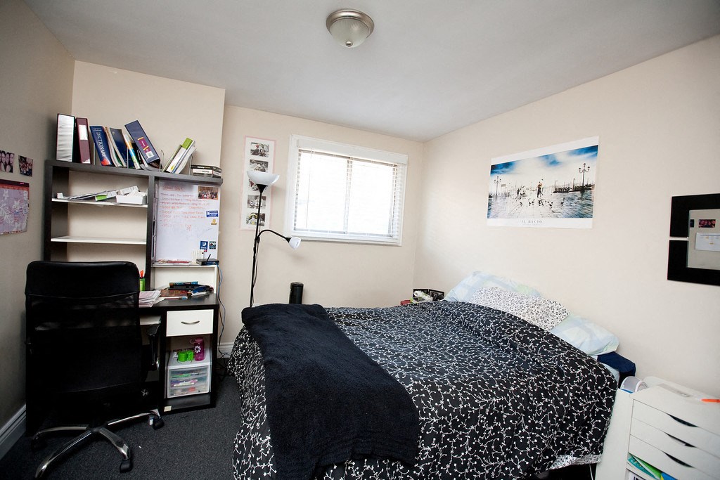 a bedroom with a bed and a desk and a window