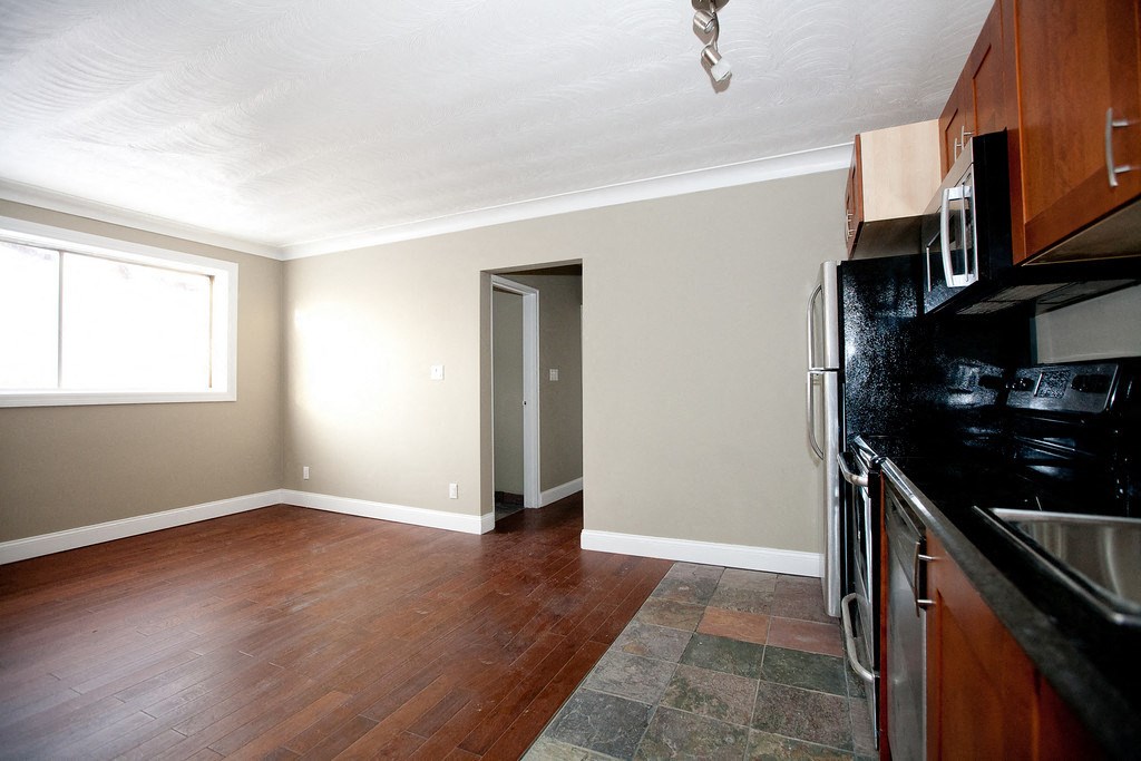 an empty kitchen and living room with wood flooring and a window